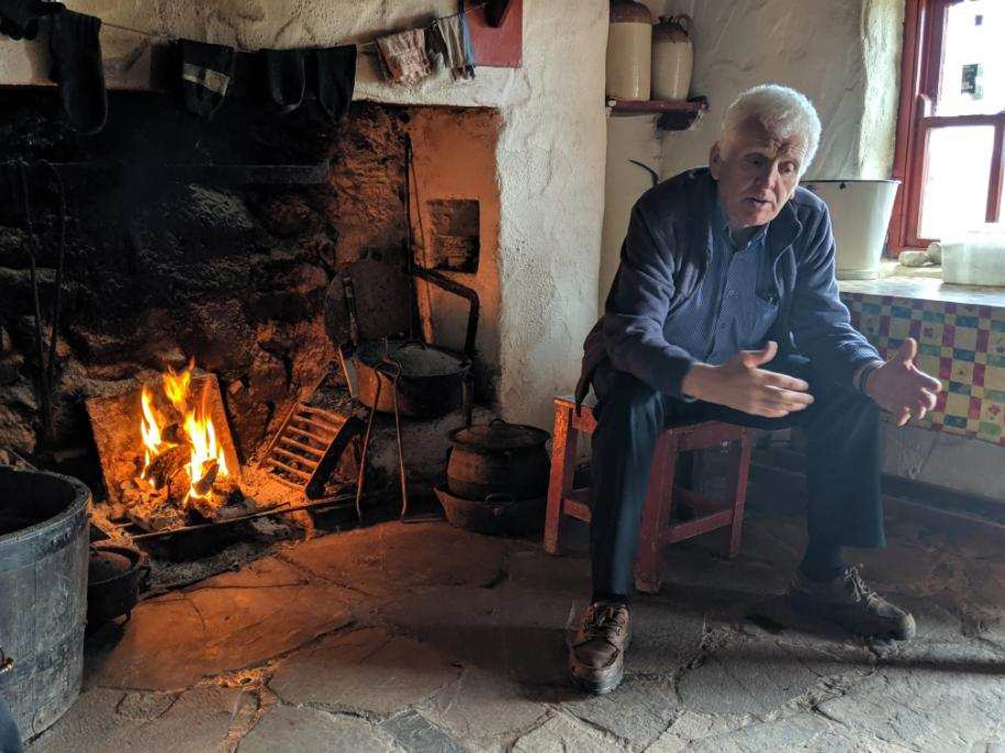 a man sitting in a chair by a fireplace