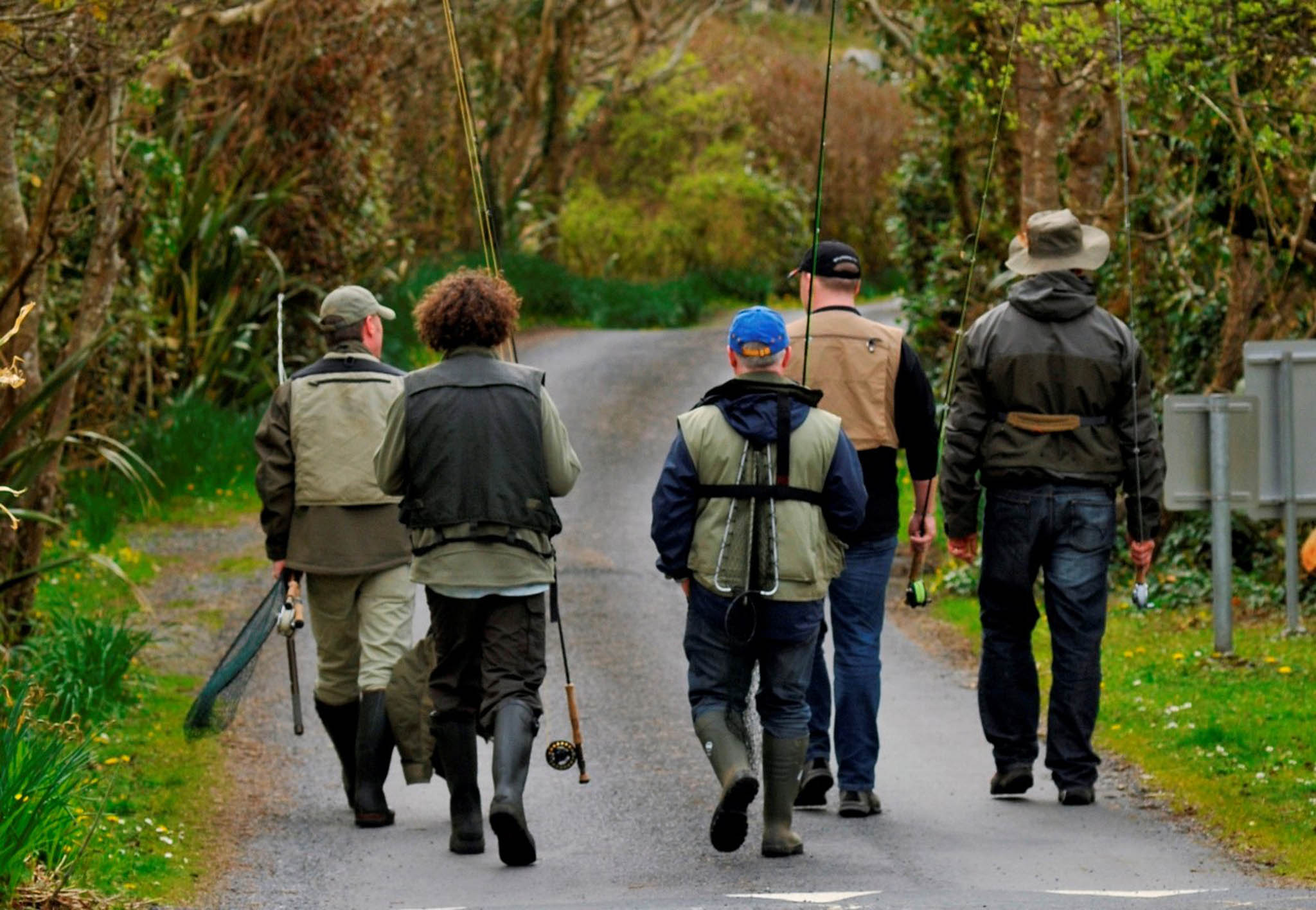 a group of men walking on a path with fishing poles